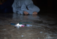 Addict with a syringe using drugs on the floor.