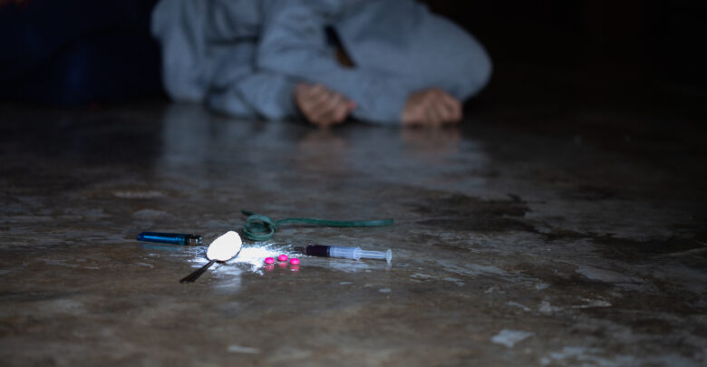 Addict with a syringe using drugs on the floor.